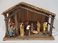 Front view of complete wooden stable with all figurines arranged inside and around it.