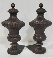 Pair of vintage heavy metal urn style bookends with ornate detail and finial tops, dark patina visible.