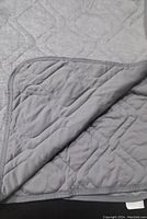 Gray quilted cooling blanket folded showing soft stitched texture and binding edge detail.