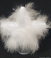 Top view of the white feathery tree topper showing the pointed top and star-shaped feather arrangement.
