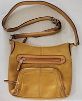 Front view of mustard yellow genuine leather crossbody bag with front zippered compartments, adjustable leather strap, and silver hardware.