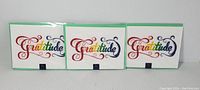 Three NIQUEA.D 'Gratitude' greeting cards, front view with green borders, arranged side by side.