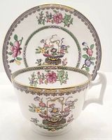 Tea cup and saucer positioned to show detailed floral pattern on both items with gold trim accents