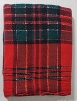 Folded view of the tablecloth showing the dense plaid pattern in red, green, black and sparkle threads.