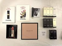 All samples arranged flat on a white surface including Chanel skin care and makeup packets and Gucci beauty sample. Various colors and packaging evident.