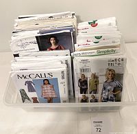 Top view photo showing all 37 uncut sewing patterns inside a plastic container. Front envelopes from McCalls, Simplicity, Burda, Vogue, Butterick, Burda are visible showing women's fashion designs.