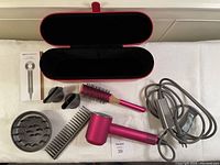 Full set laid out on white surface showing hairdryer, attachments, brush, comb, manual and case