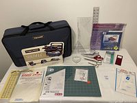 Full lot setup showing Fiskars blue project bag with multiple quilting and sewing items spread on table including rulers, scissors, cutting mat, and pins.