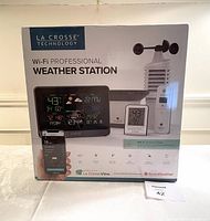 Front view of the sealed box showing product branding, display console, and outdoor sensor image