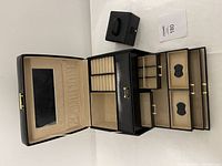 Large black leather jewelry box open showing mirror, multiple compartments including ring rolls and drawers