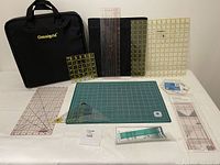 Photo of all items displayed with Omnigrid black project bag, rulers, and green cutting mat arranged