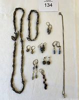 Full view of all sterling silver jewelry including matching necklace, bracelet, and multiple pairs of earrings with gemstone accents on white background.