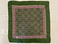 Full view of vintage Liberty of London green and fushia floral silk scarf laid flat showing overall pattern and border with a muted green outer edge.