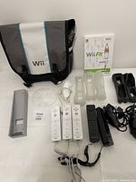 Overview photo showing all accessories including Wii case, Wii Fit game, remotes, covers, sensor bar, and charging dock arranged on white surface