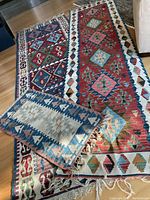 Three kilims overlapped on hardwood floor showing overall sizes, patterns, and colors