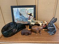 Overall group view showing eagle head carving, wood bear and elephant, stone rabbit, wooden toy car, and framed painting