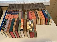 Full overview of all books in the lot arranged on table, showing spine designs and conditions.