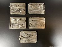 Top view showing all five pewter collectible Boeing belt buckles depicting different aircraft and scenes