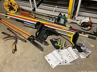 Overview of garden tools including chainsaw, brush cutter, clippers, hand tools, extension cords, and lubricant bottles.