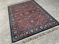 Full view of rug laid flat showing red field and border design