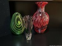 Three hand-blown glass vases displayed on a black surface, showing front views and arrangement for scale