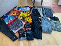 Overview photo showing colorful cycling jerseys, pants, and shorts laid out on floor