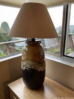 Full view of lamp on wooden table near window showing overall size and shape with shade.