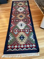 Full view of vintage kilim rug runner laid on hardwood floor showing full length, pattern and fringed ends