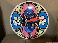 Front view of round clock showing colorful Peter Max design with red hands and General Electric and Peter Max logos