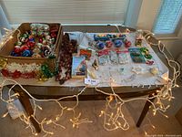 Wide shot of assorted vintage Christmas ornaments and decorations on a table with holiday lights around the edge.