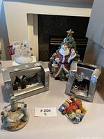 Photo showing the full lot of Christmas-themed ceramic figurines including Santa Claus cookie jar and boxed miniature village people figurines.