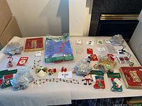 Overview of Christmas accessories laid out on a table including silver star ornaments, stockings, angel ornaments, light garland, and boxed sets.