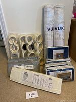 Photo showing multiple packaged white plastic rings for hanging storage, rolled white fabric organizers with label VUI VUKI, and several boxed cloth storage boxes.