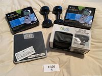 Lot showing two boxed digital therapy machines, blue dumbbells, weighing scale, and travel kit pouch