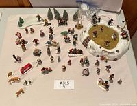 Full spread of all Lemax Christmas village figurines and pieces laid out on table showing quantity and condition