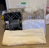 Full lot showing Martex bedding items bagged and three throw blankets arranged for display