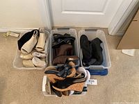 Three plastic containers filled with various women's shoes, sizes 6 and 7, arranged on carpet floor near white walls.