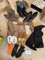 Overview of entire lot showing multiple boots, slippers and gloves arranged on floor with boxes visible in background