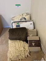 Multiple bedding sets and blankets displayed stacked with visible packaging and crochet blanket detail