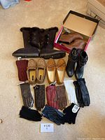 Brown fur-lined UGG boots, various boots, slippers, and an assortment of gloves laid out on a beige carpet.