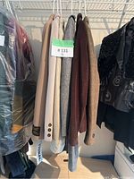 Five wool and cashmere blazers hanging on a rack, showing different colors and textures.