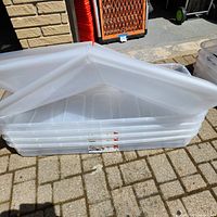 Stacked clear plastic bins with bi-fold lids partially unfolded, showing size and shape.