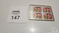 Block of four Elvis Presley 29 cent postage stamps in a plastic holder with auction lot card visible.