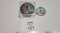 Front view of autographed hockey puck in display case next to 2.5 inch button with Tony Esposito image.