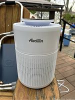 Front view of the Aircillin air purifier showing the brand logo and perforated vent design on white cylindrical body.