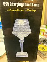 The front of the box showing the LED touch lamp with a diamond cut style clear lampshade and base, described as USB charging touch lamp for atmosphere making.