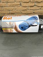 Front view of the rolled blue exercise mat with packaging showing a person exercising and product name 'Exercise Mat'.