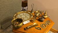 Photo showing multiple brass ware items including tray, bell, mini kettles, vase, shoe horn, and small brass figurines
