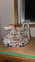 Full view of unique duck-shaped vintage Japanese porcelain teapot with floral hand-painted decoration in orange and blue.