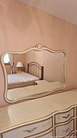 Front view of Drexel wall mirror showing carved frame and reflection of bed and lamp.